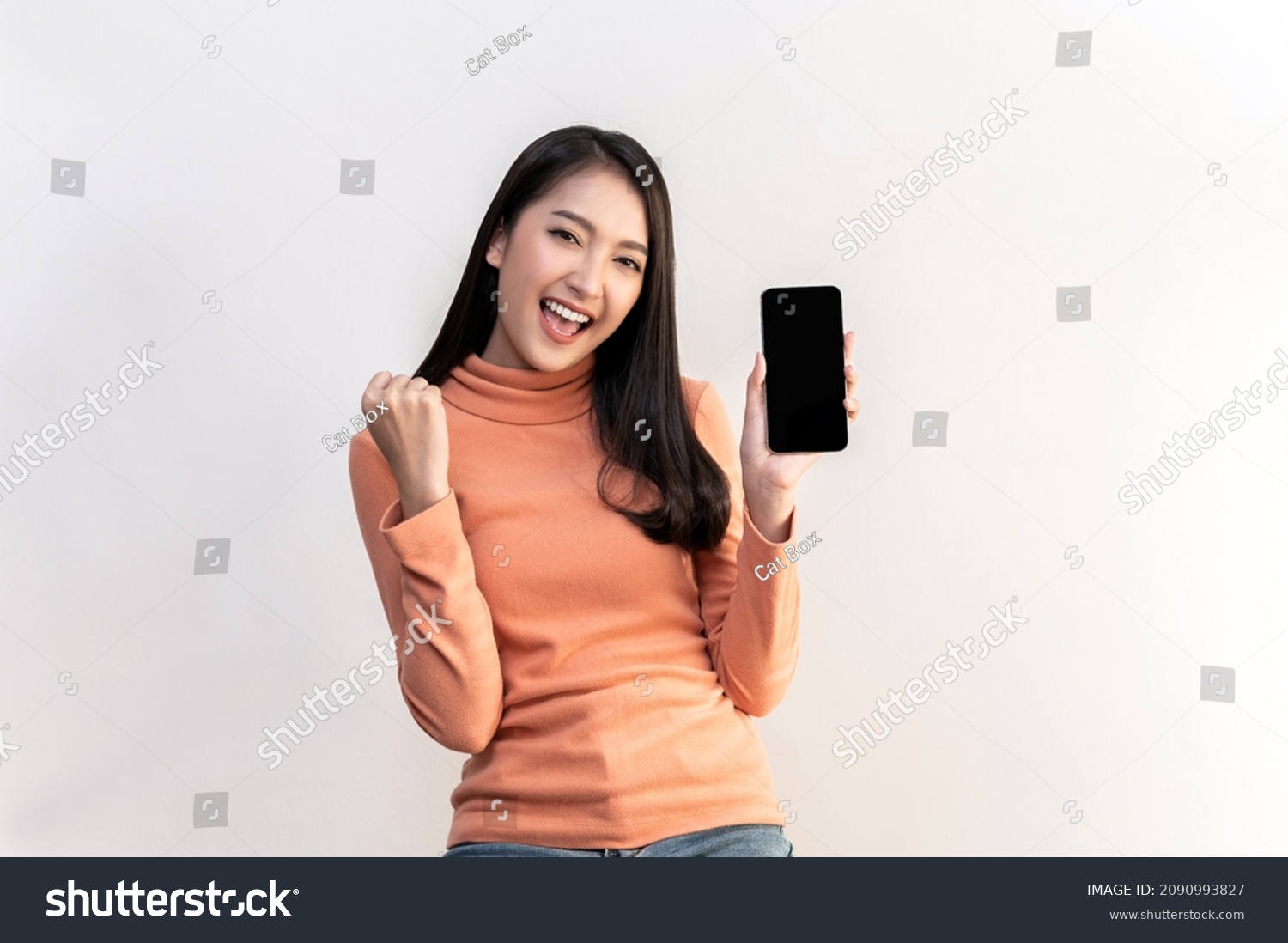 Portrait photo of young beautiful Asian woman feeling happy or surprise shock and holding smart phone with black empty screen on white background can use for advertising or product presenting concept. #2090993827