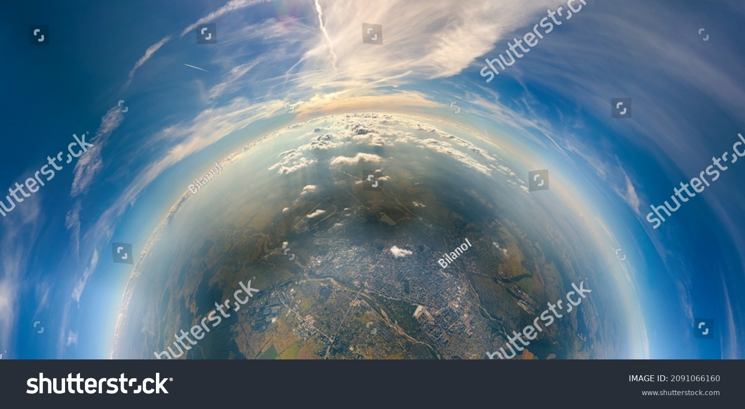 Aerial view from airplane window at high altitude of little planet distant city covered with layer of thin misty smog and distant clouds in evening #2091066160