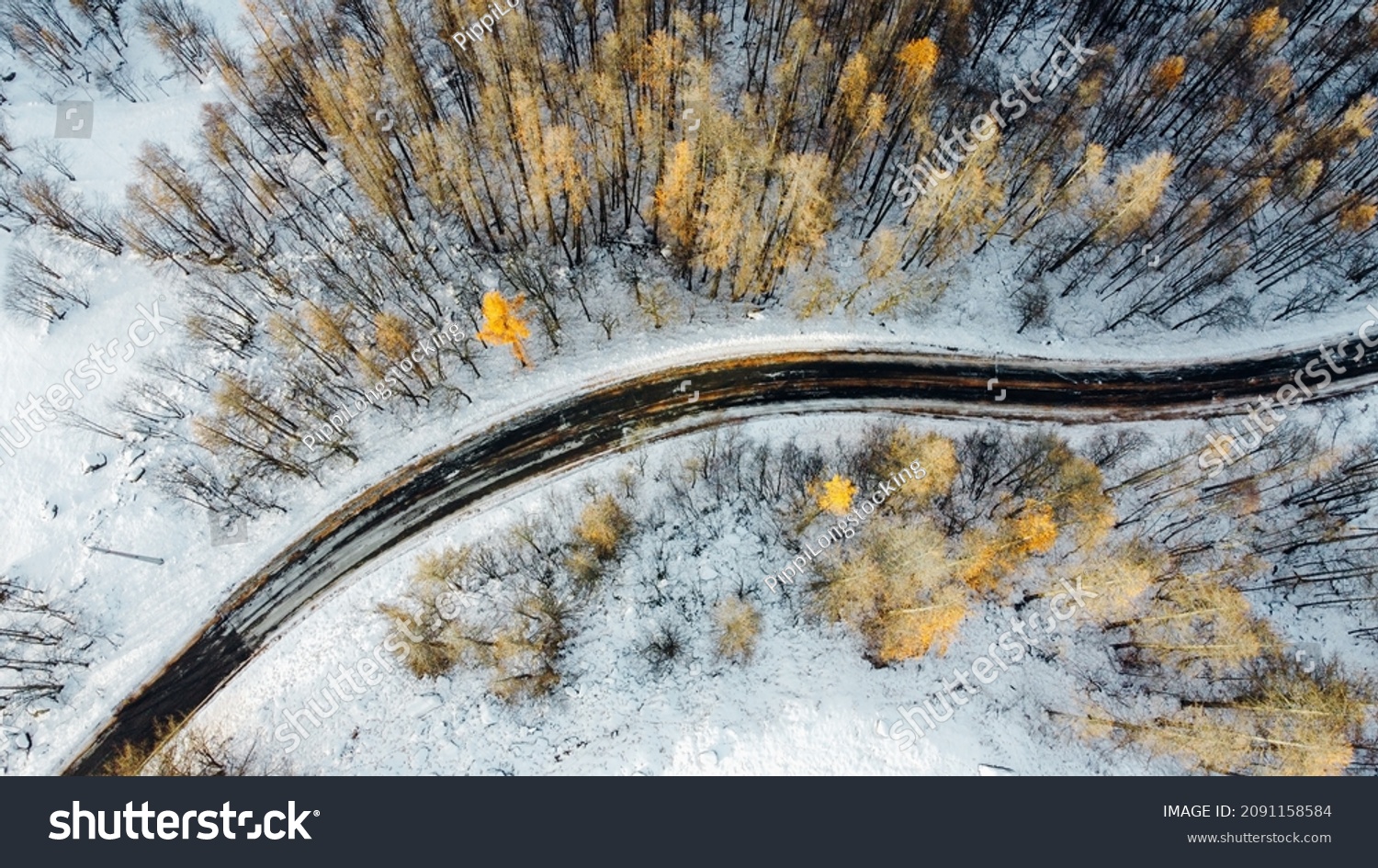Aerial high angle view of narrow winding curvy mountain road among the trees in winter forest. Snowy landscape, bird's eye view. #2091158584