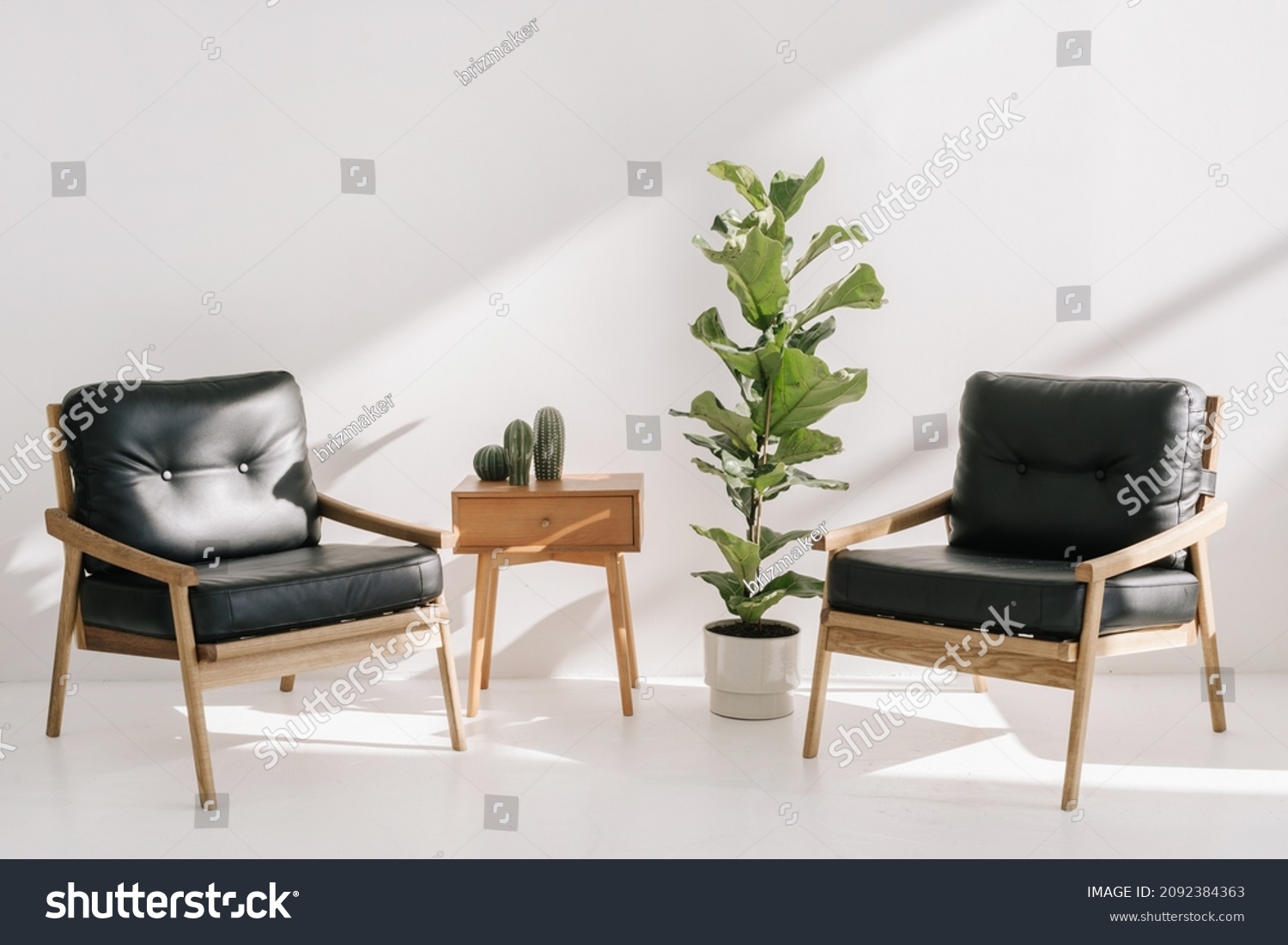 Home decor on side table with drawer standing near two leather armchairs and potted house plants. Recreation, relaxation concept. Wooden table and office chairs in bright copy space living room #2092384363