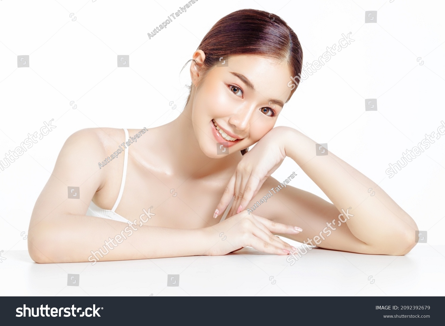 Asian woman with a beautiful face gathered in a brown ponytail and clean fresh smooth skin. Cute female model with natural makeup and sparkling eyes on white isolated background. #2092392679