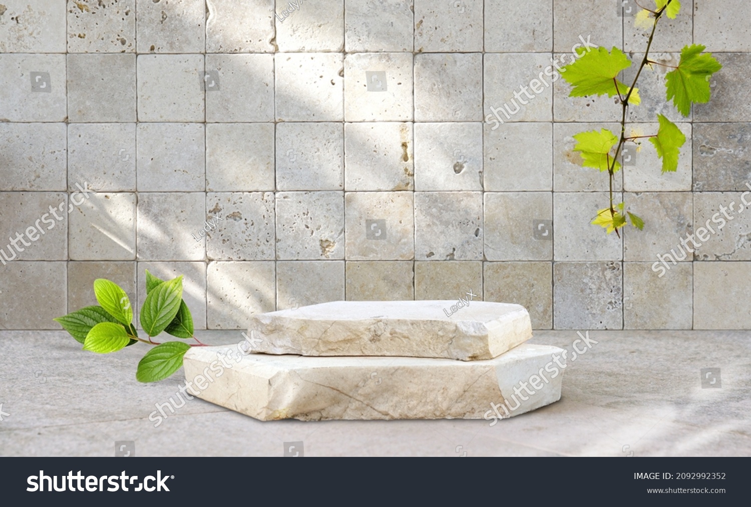 Original template for spa product presentation. Pedestal of marble slabs and branches with green leaves  against  background of wall in bathroom with masonry in light beige colors. #2092992352