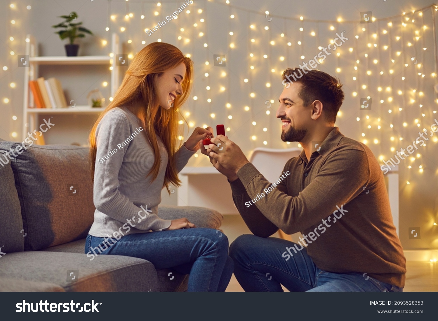Will you marry me. Couple making love promise to each other on cozy evening at home. Happy woman getting romantic marriage proposal. Young man proposing to girlfriend and giving her engagement ring #2093528353