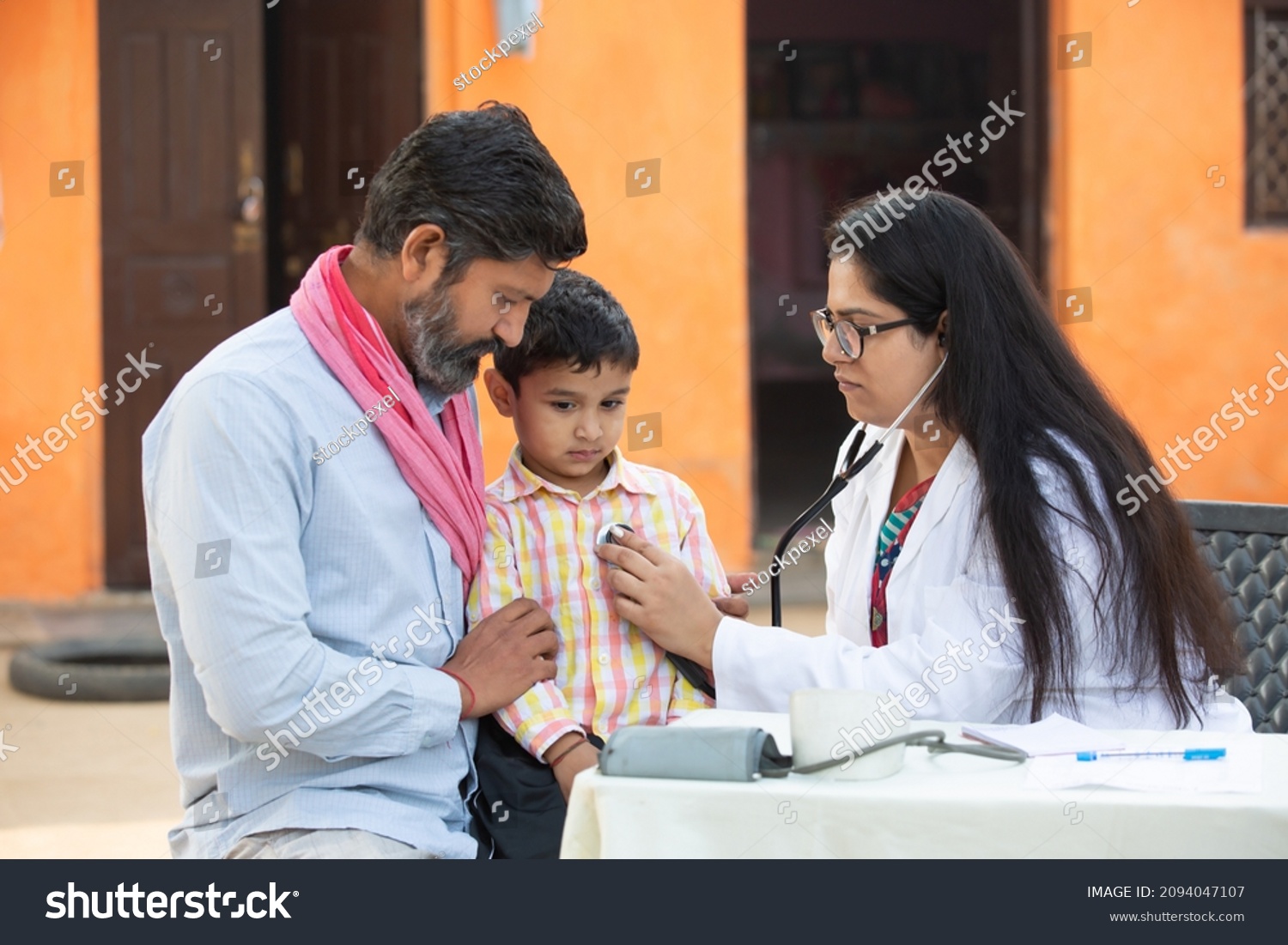 Indian female doctor with stethoscope checking little child patient heart beat or breath at village, Kid with his father getting examine by medical person, Rural India healthcare concept #2094047107