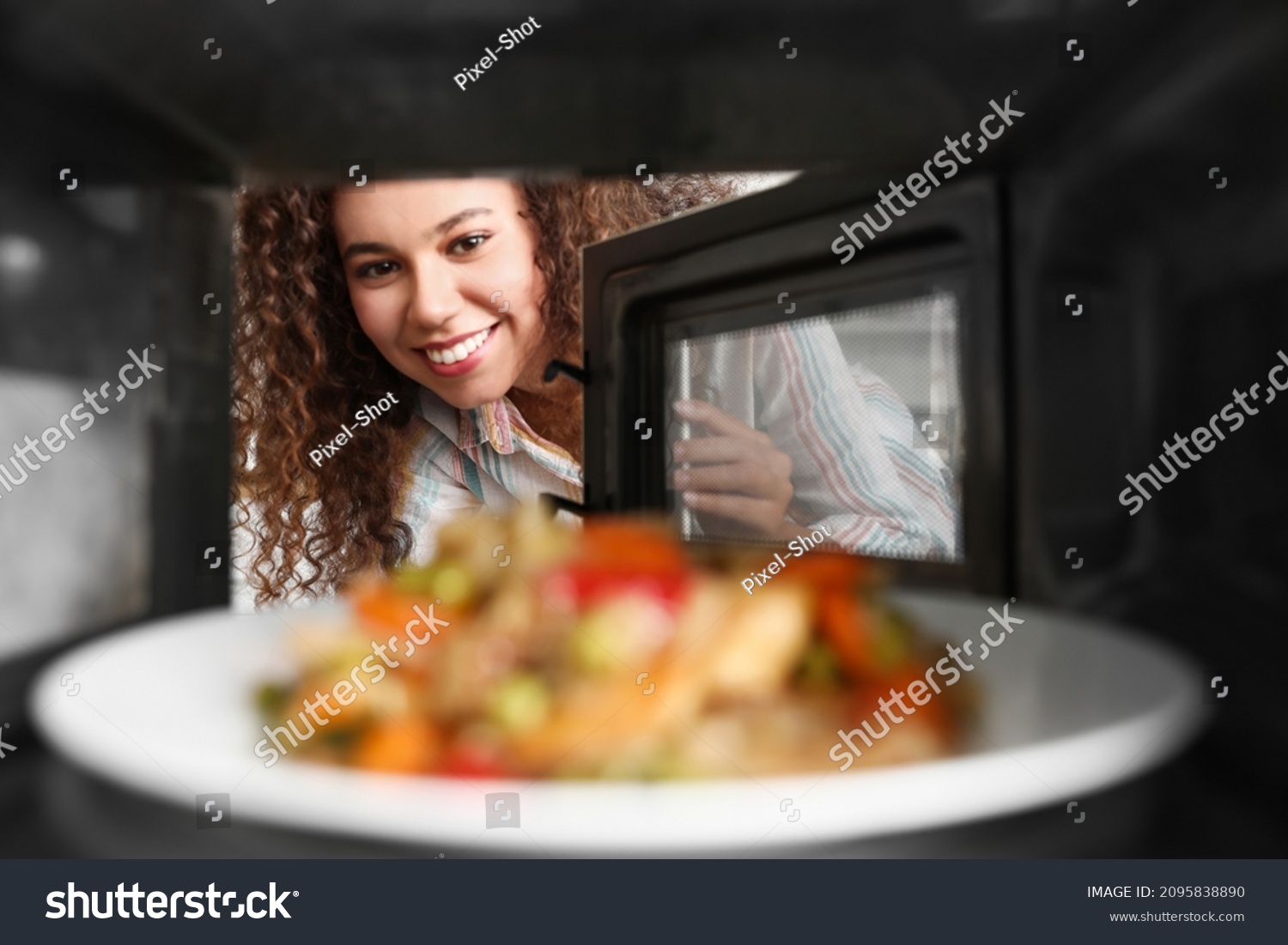 Young African-American woman heating food in microwave oven, view from inside #2095838890
