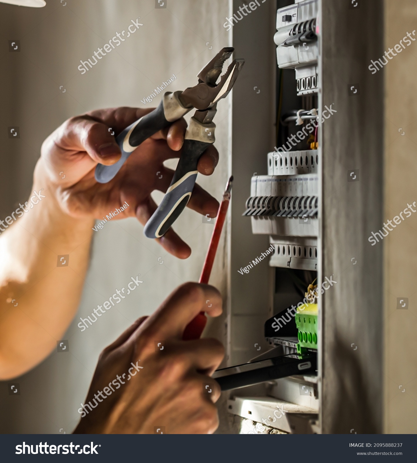 Man, an electrical technician working in a switchboard with fuses. Installation and connection of electrical equipment. Professional with tools in hand. concept of complex work, space for text. #2095888237