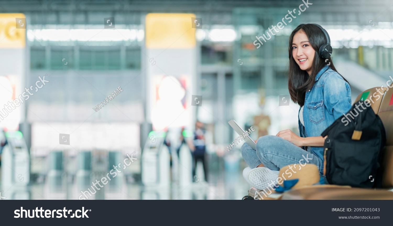 travel vacation concept,pov asian female woman wear headphone hand use laptop hand wave greeting to camera with cheerful and happiness,asian female sit wating at wating area in airport terminal #2097201043