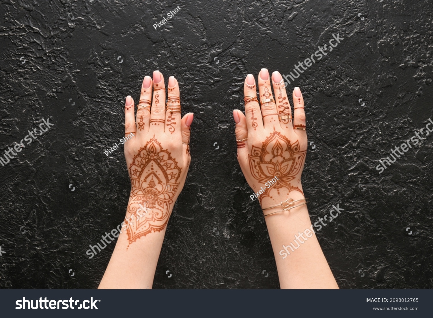 Beautiful female hands with henna tattoo on black textured background #2098012765