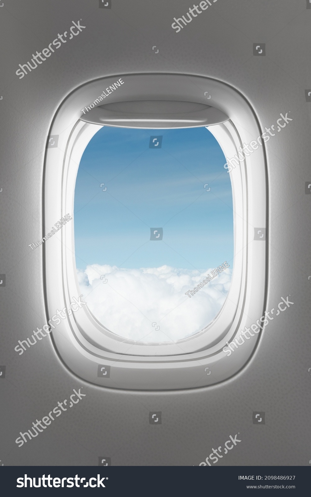 looking through a big jet passenger plane window, above the clouds #2098486927