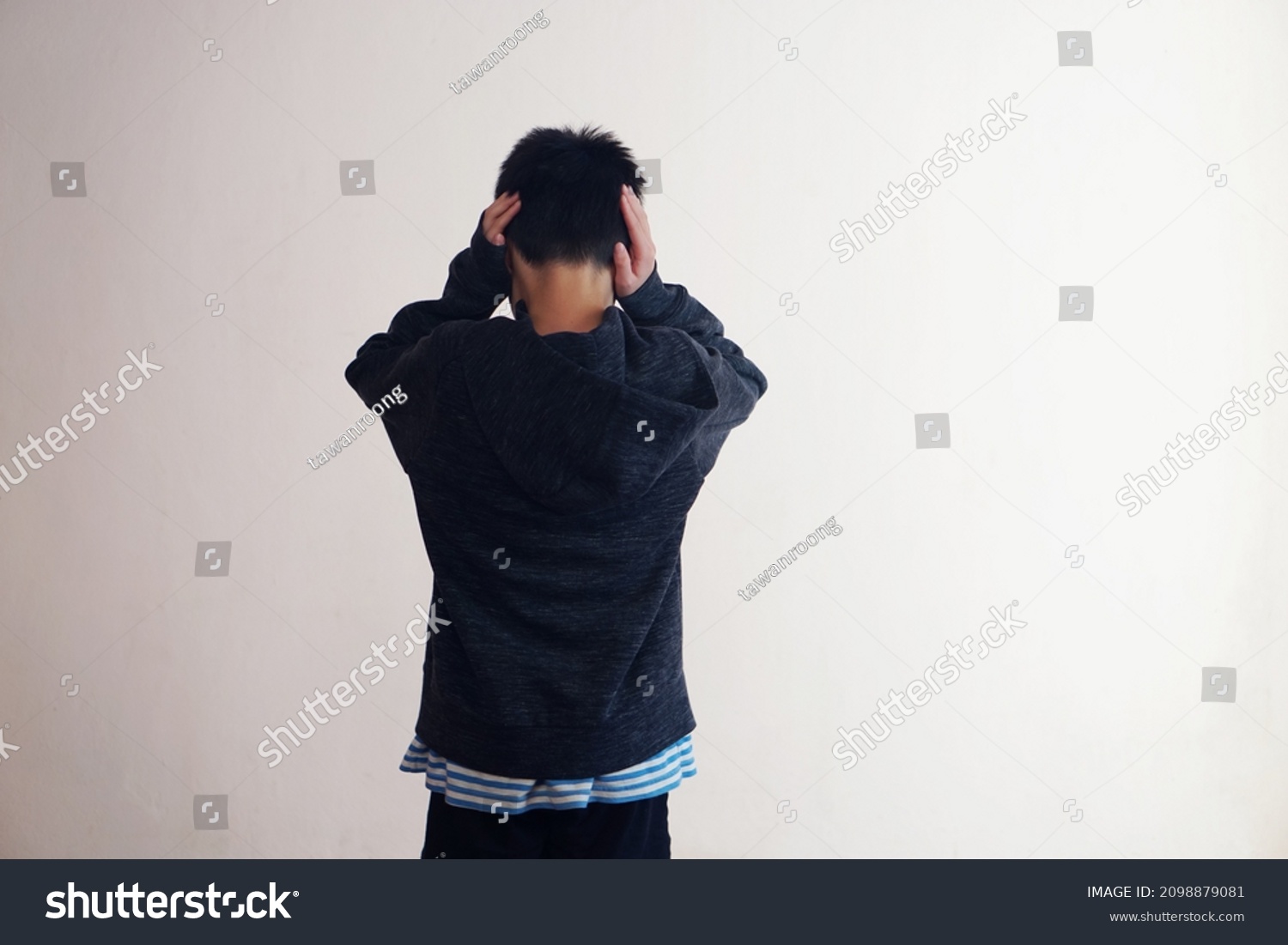 Back view of young boy stands and close his ears with hands, faces to the wall. Concept :  Depression , anxiety disorder angry, disobey, don't want to hear, naughty kid.                #2098879081