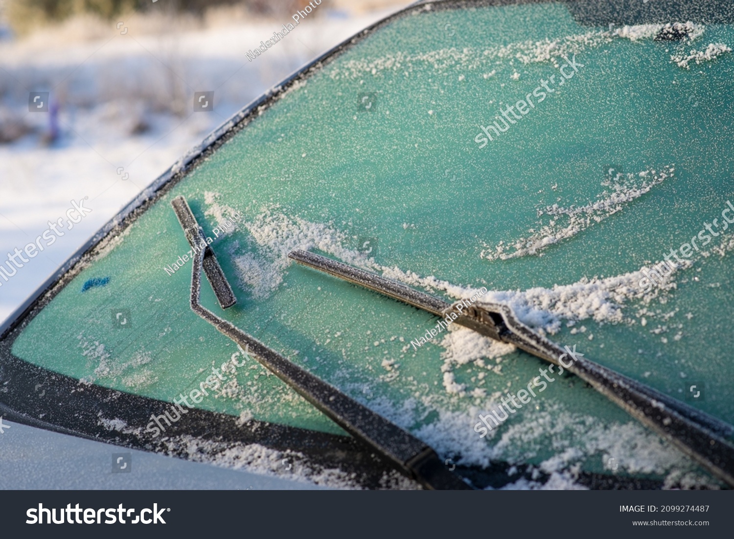 Snow-covered car windshield. Wipers and washers in frost. Frost and cars. #2099274487