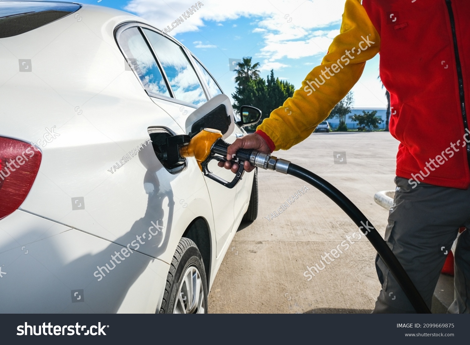 Man pumping gasoline fuel in car at gas station and being fill gas tank of white car in gas station, Concept of Global Fossil Fuel Consumption, Rising gasoline prices, Copy Space. #2099669875
