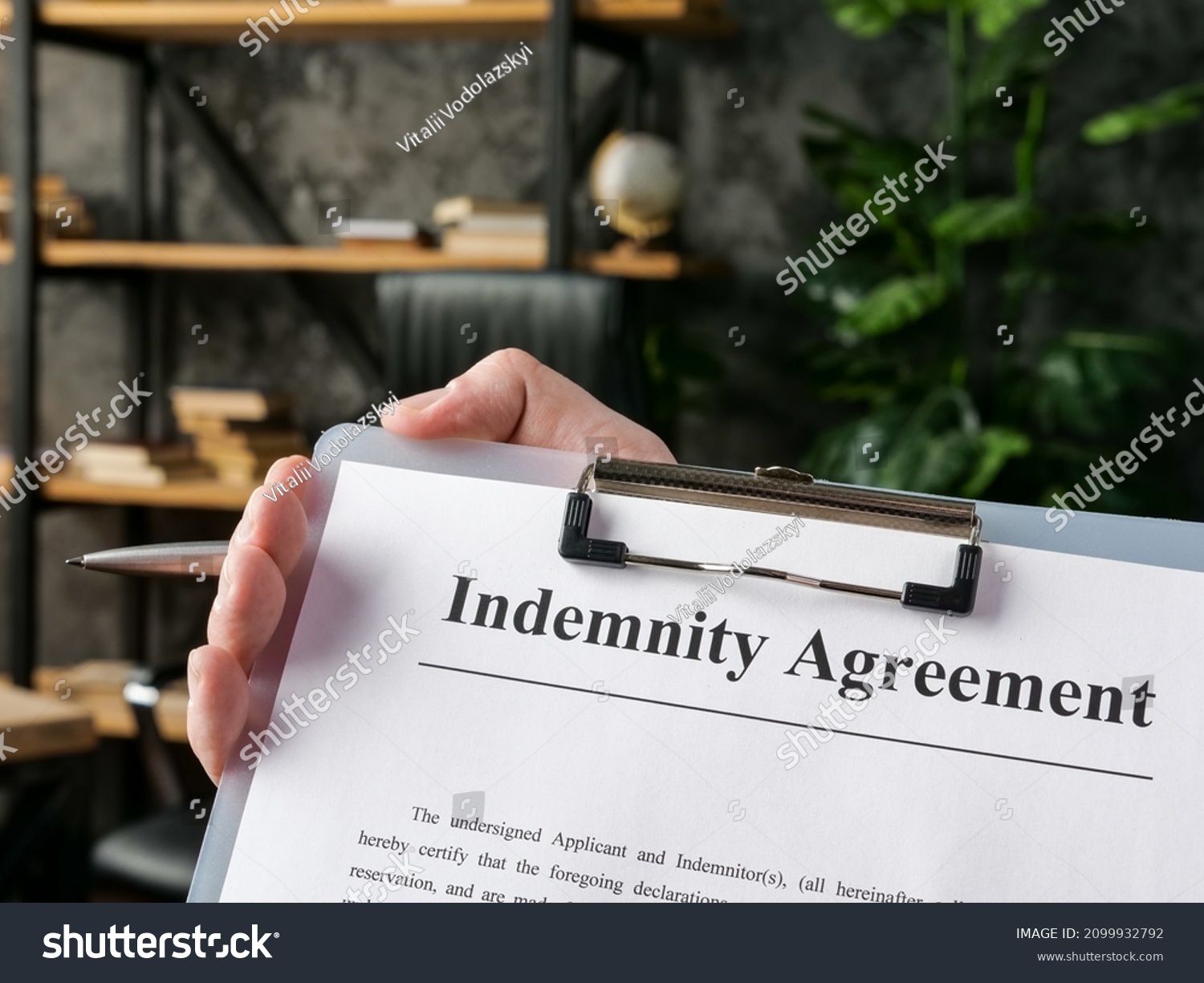 Hand holds indemnity agreement for signing in the office. #2099932792