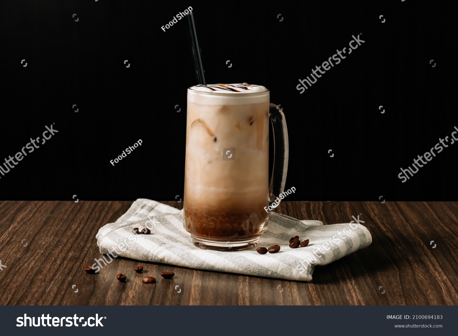 Iced mocha coffee with cream in a tall glass and coffee beans, portafilter, tamper and milk jug on dark wooden background. Cold summer drink. #2100694183