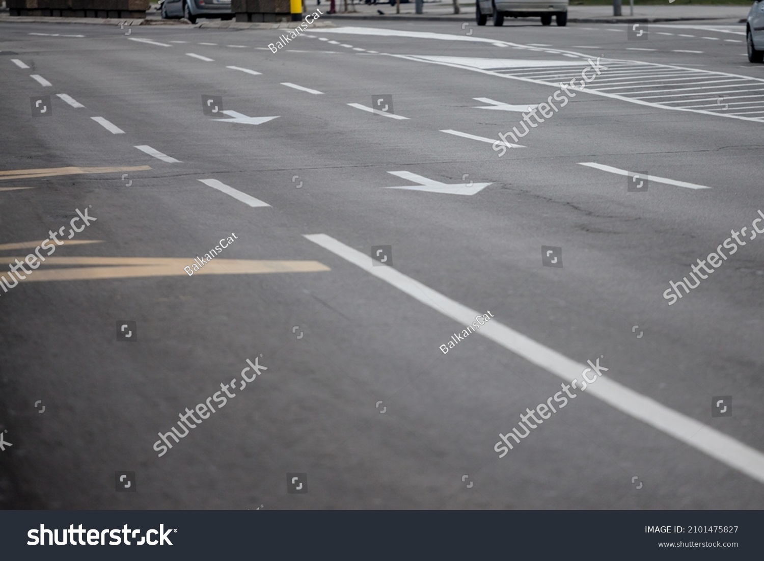 Selective blur on lane markings with painted directional arrows on thru lanes on asphalt, on a city urban road used for heavy traffic, in Europe, abiding by european standards. 

 #2101475827