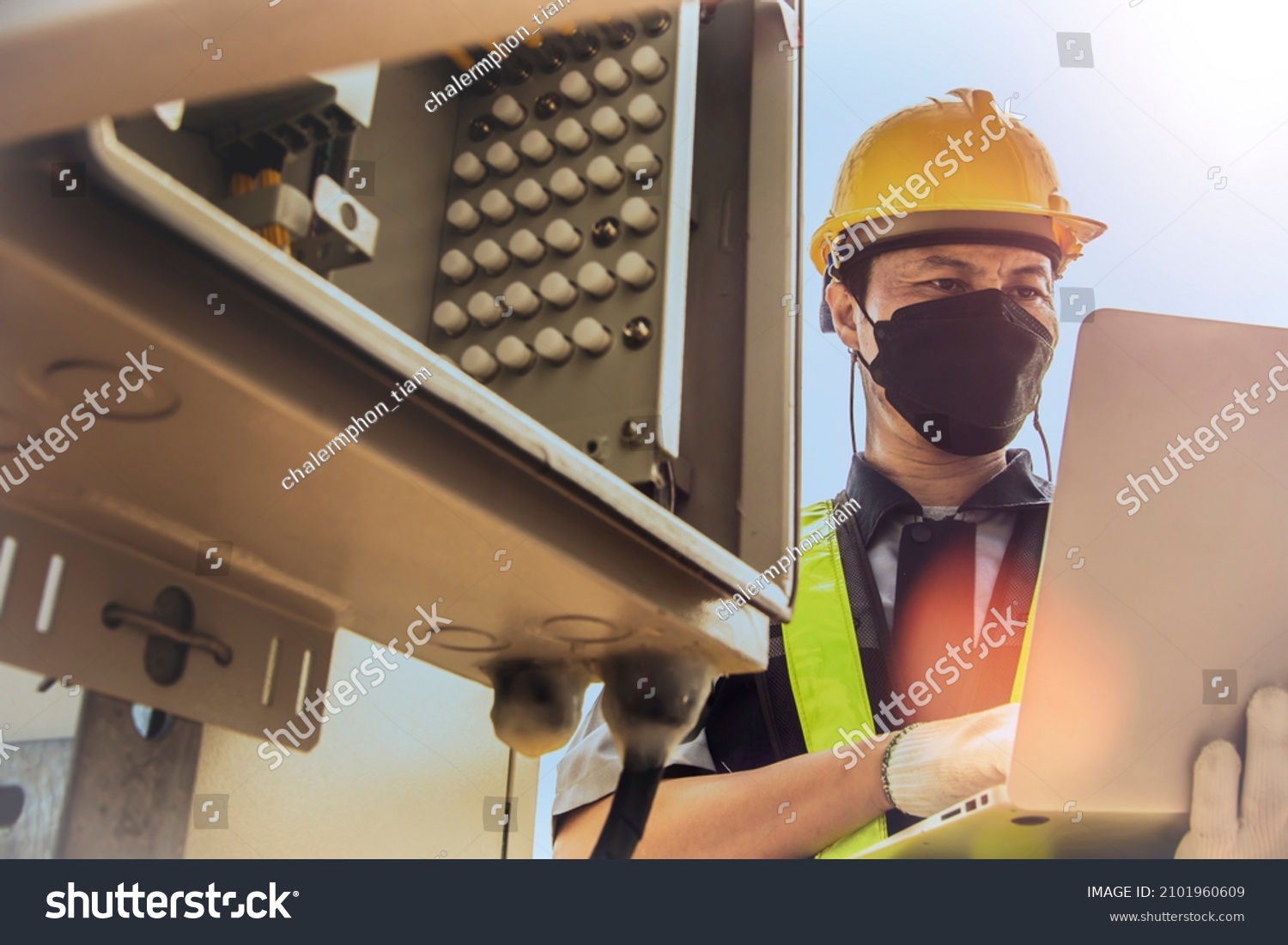 Electronic worker man wearing mask, skilled control system, control cabinet, station, signal tower. Telecom uses a laptop to check the telecommunication circuit board system. #2101960609