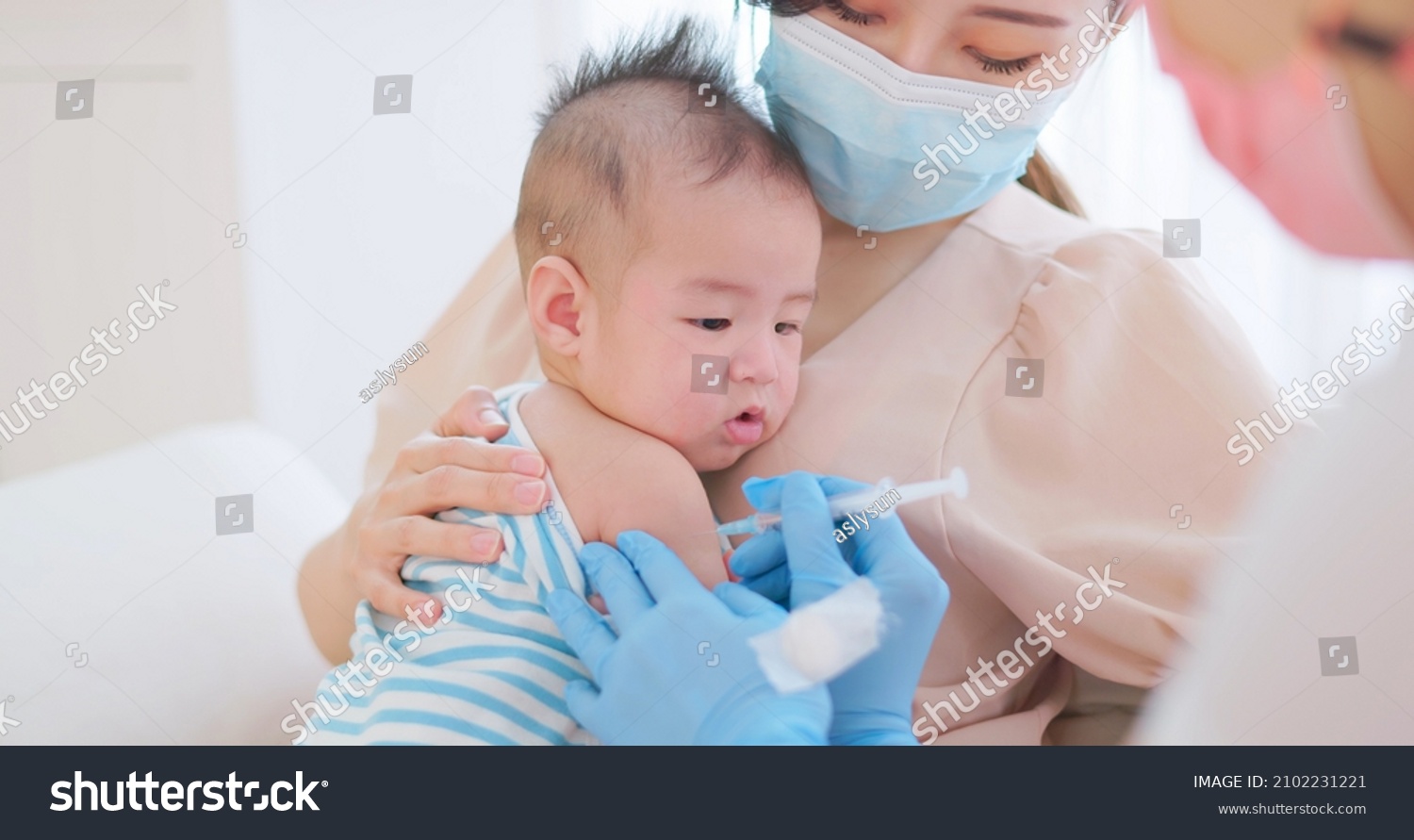 authentic shot of asian mother wearing face mask holds her baby for vaccinated by doctor #2102231221