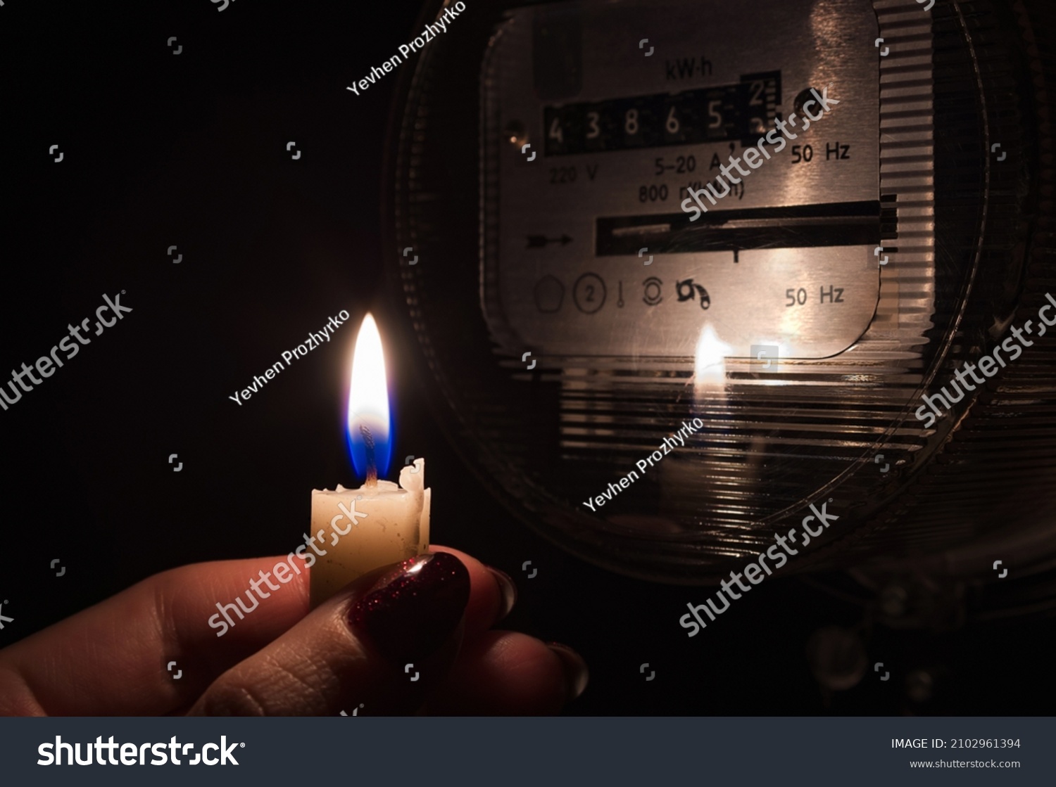 Candle shining light in the dark near electricity meter during power outage at home. Blackout city, no electricity symbolic image. #2102961394