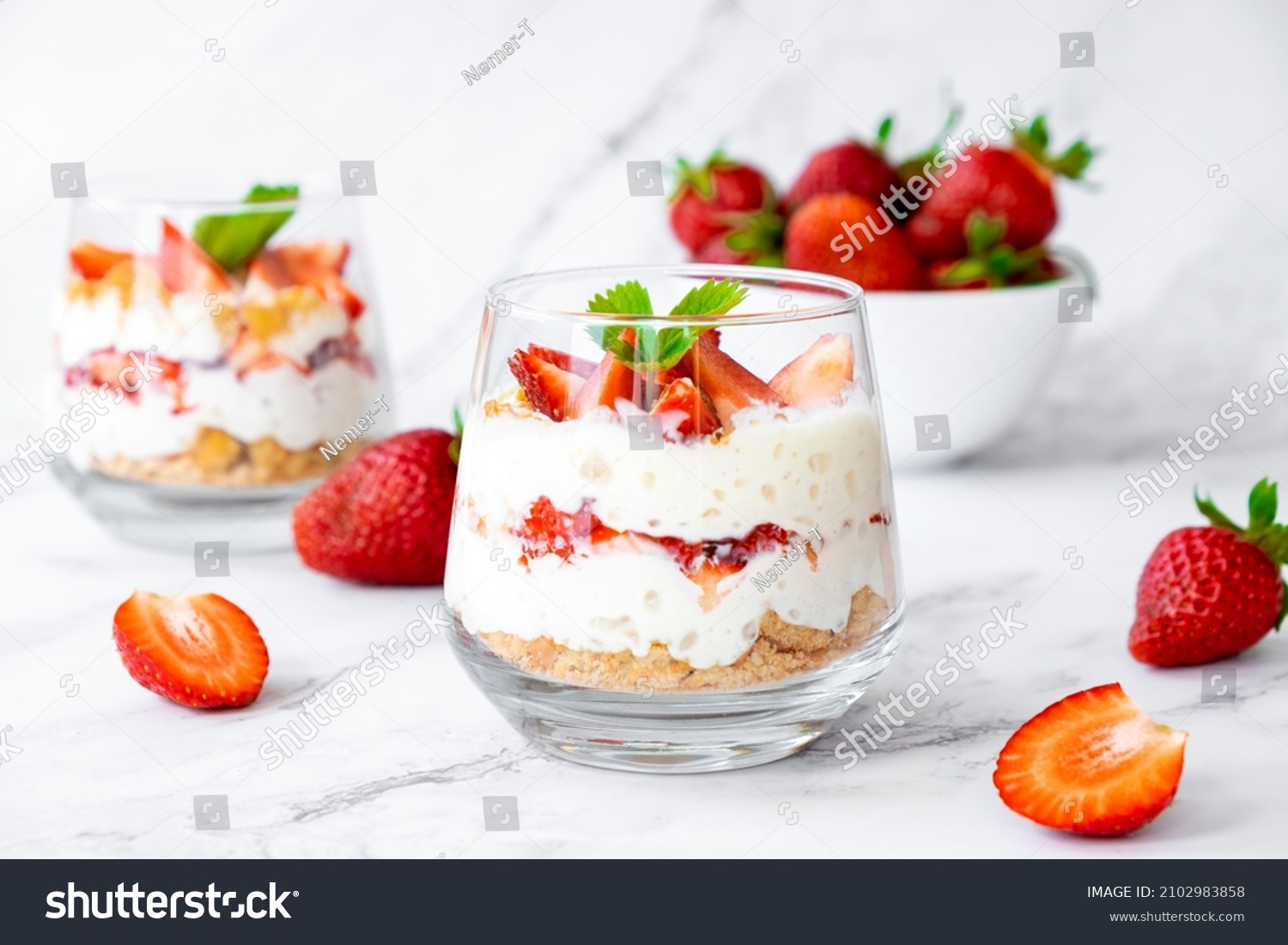 Italian strawberry tiramisu dessert with mascarpone and whipped cream, savoyardi crumb and fresh strawberry in glass on marble. Recipe of simple dessert, cheesecake, pudding or berry trifle cake. #2102983858