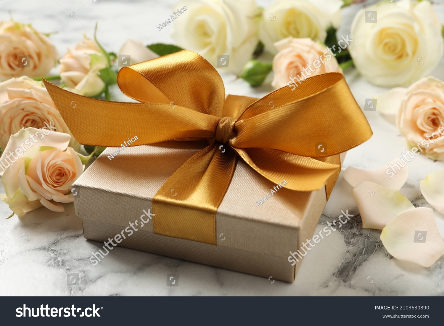 Golden gift box and beautiful roses on white marble table #2103630890