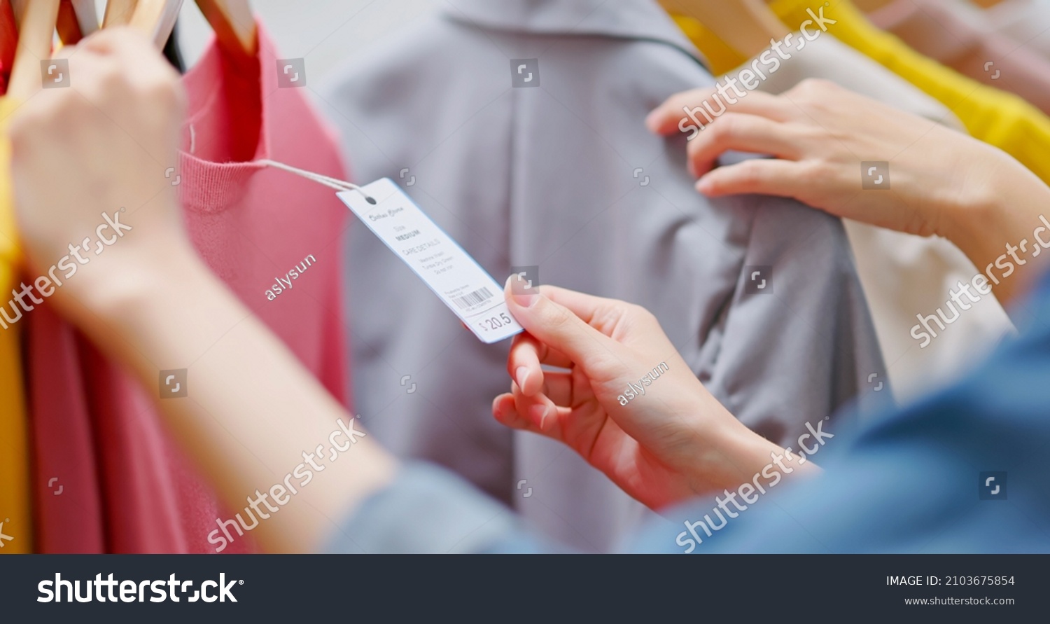 close up of asian women looking at clothes and price tag while shopping at store #2103675854