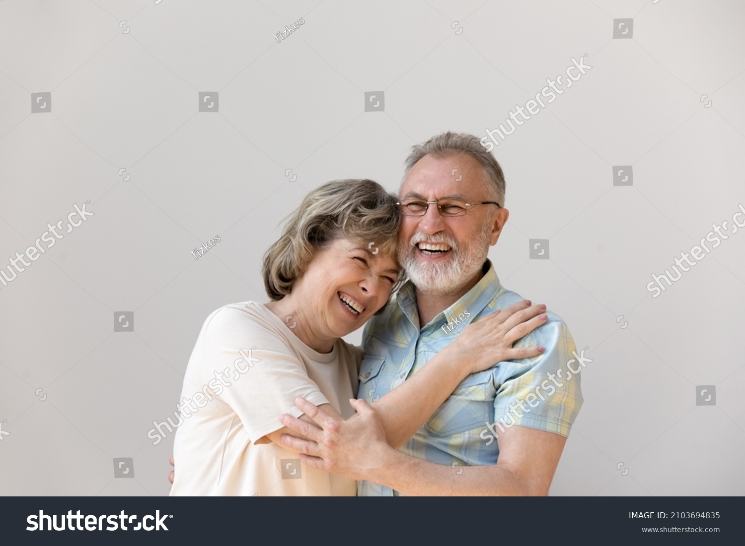 Sincere laughing bonding happy middle aged senior married couple cuddling, having fun enjoying communicating, isolated on white wall, showing candid loving feelings, good family relations concept. #2103694835
