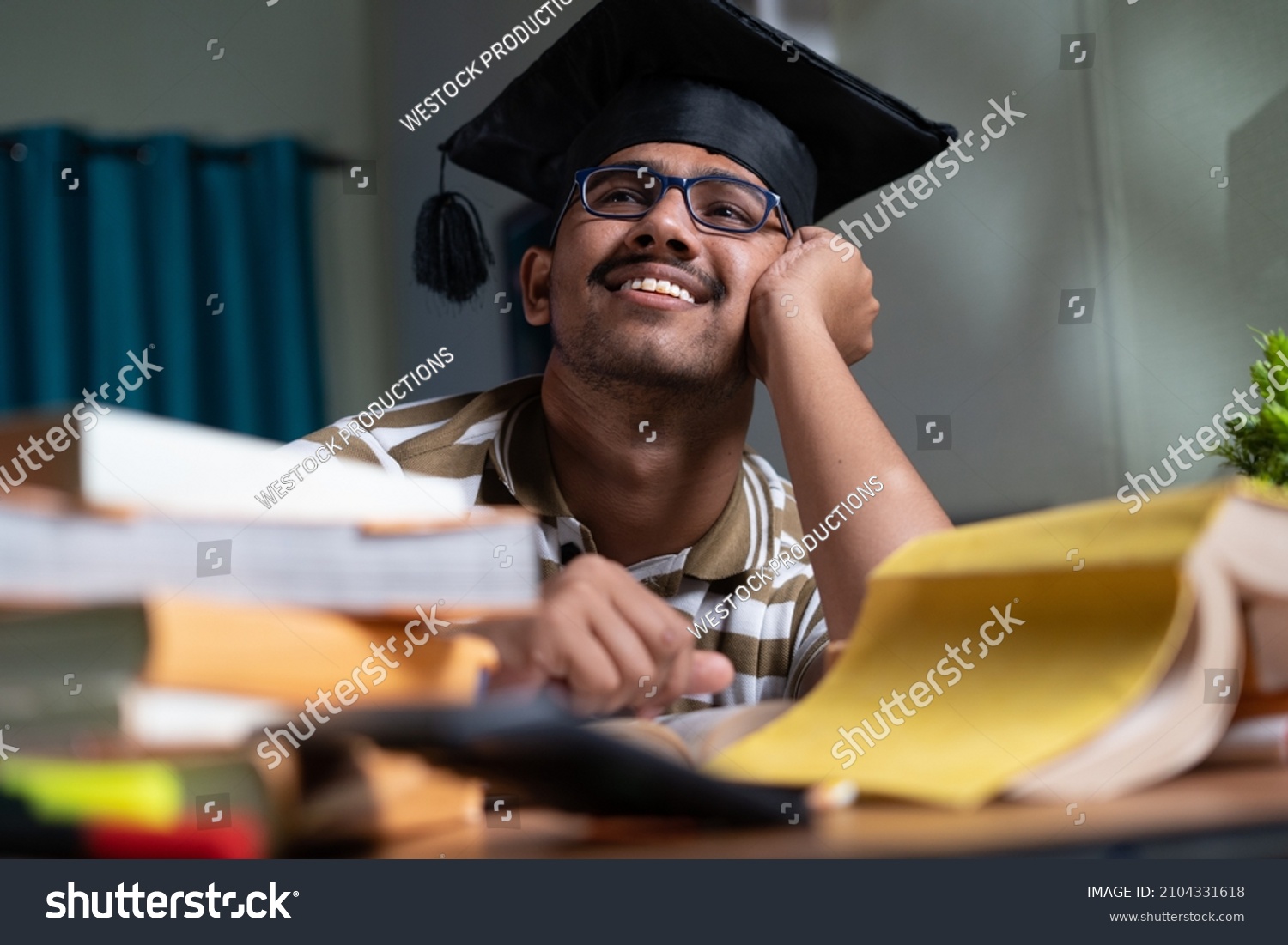 young student dreaming about graduation while studing book or preparing for examination at home - concept of daydreaming and future career goal and education. #2104331618