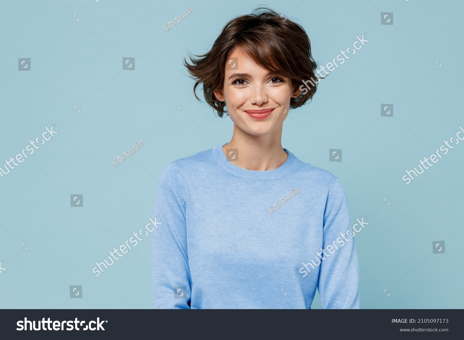 Young smiling fun happy caucasian european attractive cute woman 20s in casual sweater looking camera isolated on plain pastel light blue color background studio portrait. People lifestyle concept. #2105097173