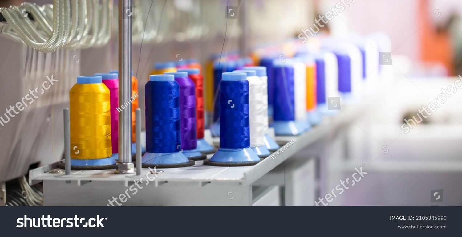 Colorful rows spools of thread stand on embroidery machine in garment industry. #2105345990