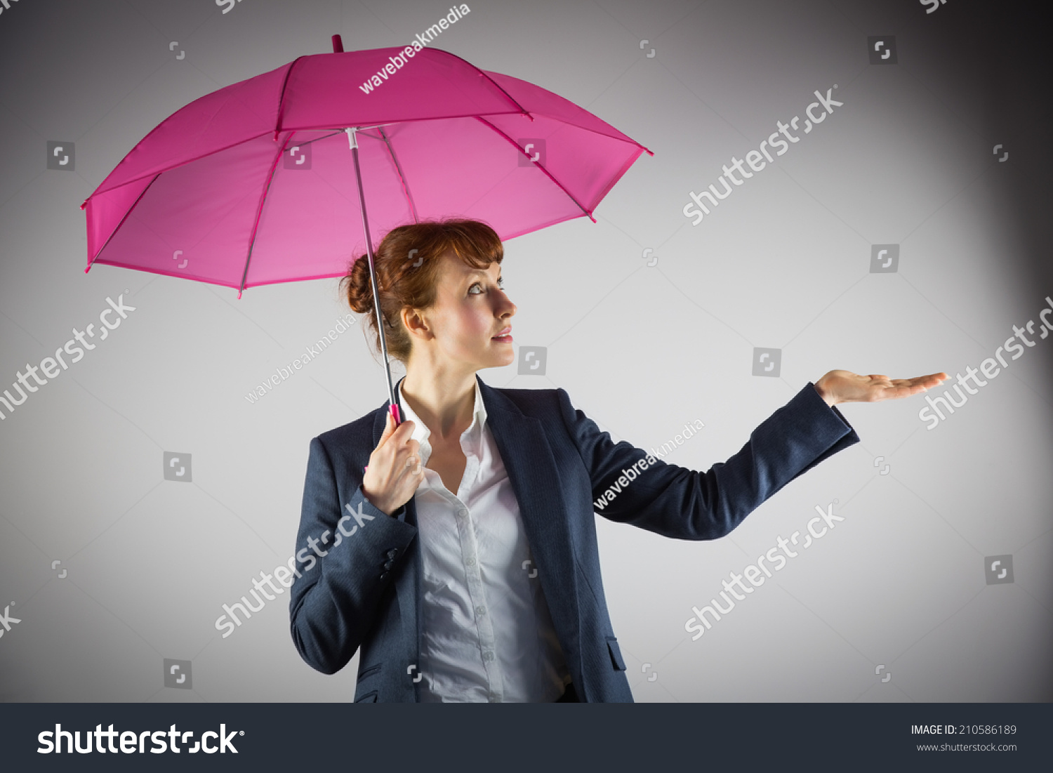 Smiling businesswoman holding pink umbrella on grey background #210586189