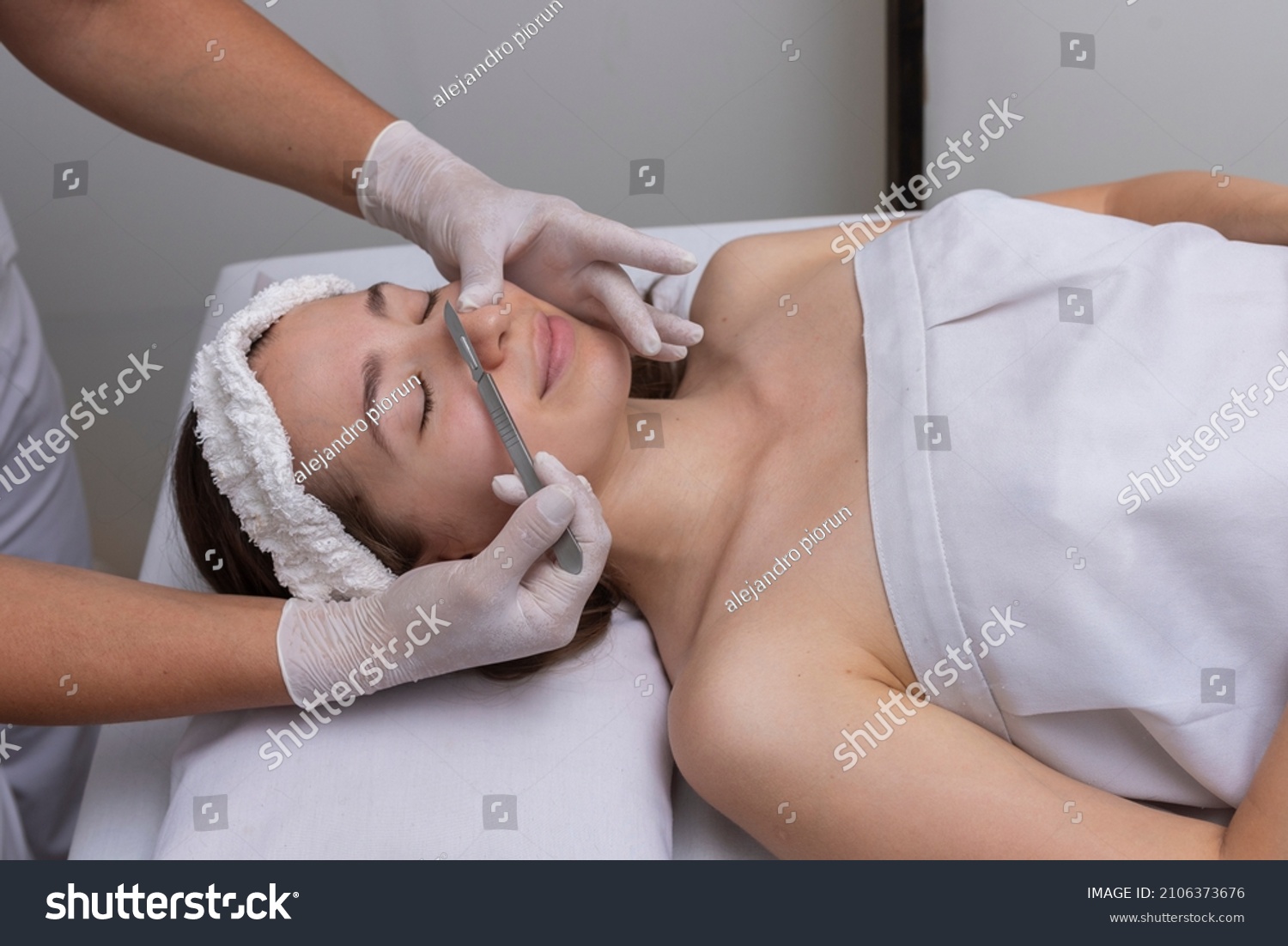 young woman lying on a stretcher in an aesthetic center performing beauty treatment and facial aesthetics with dermapen and dermaplaning techniques #2106373676