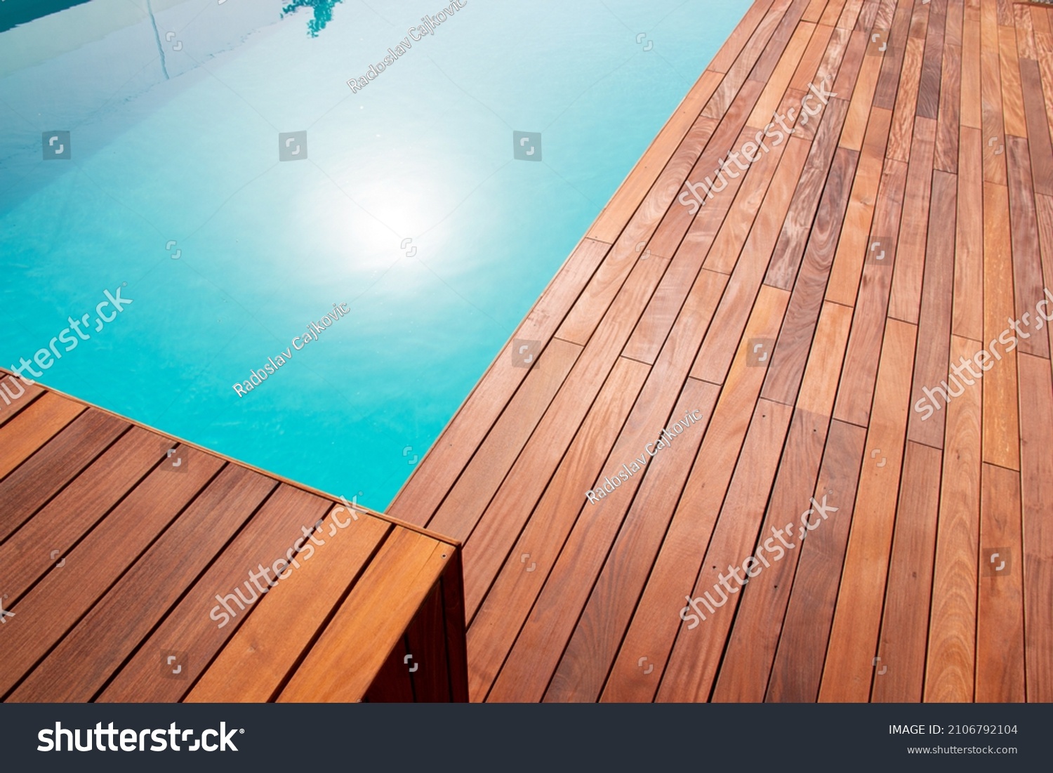 Texture with tiled wooden decorative planking, hardwood ipe pool deck shining sun reflecting on the water #2106792104
