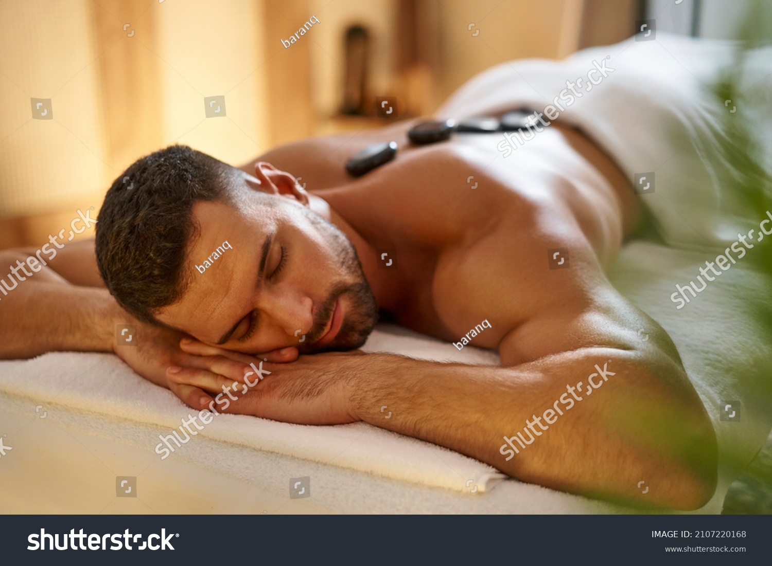Young man having a hot stone lastone massage at spa #2107220168
