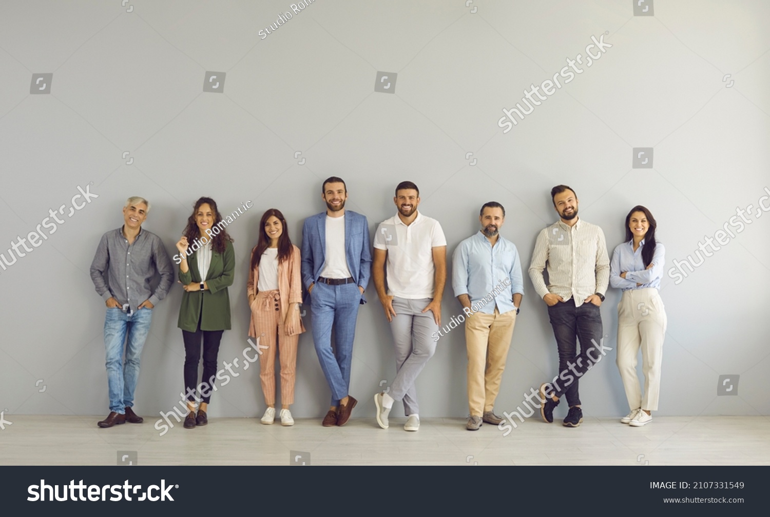 Full body portrait of happy business people in smart and casual clothes. Full length group of senior and young Caucasian men and women posing against grey studio wall. Clothing and fashion concept #2107331549