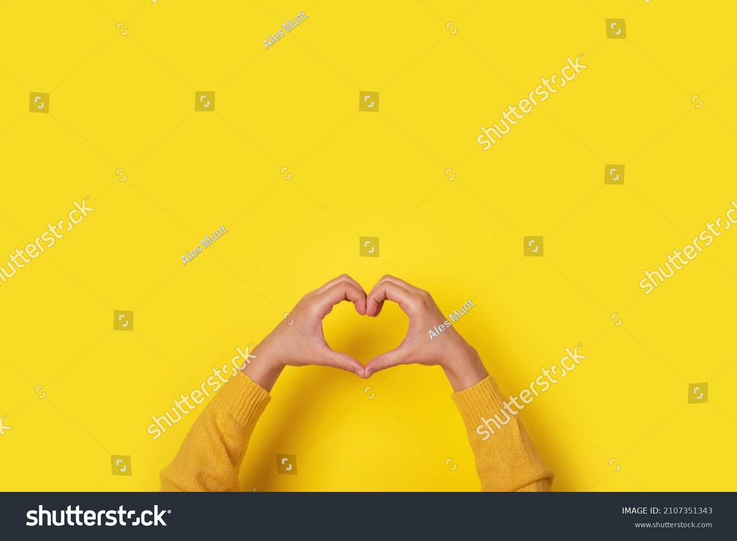 Hands making heart shape, love symbol over yellow background #2107351343