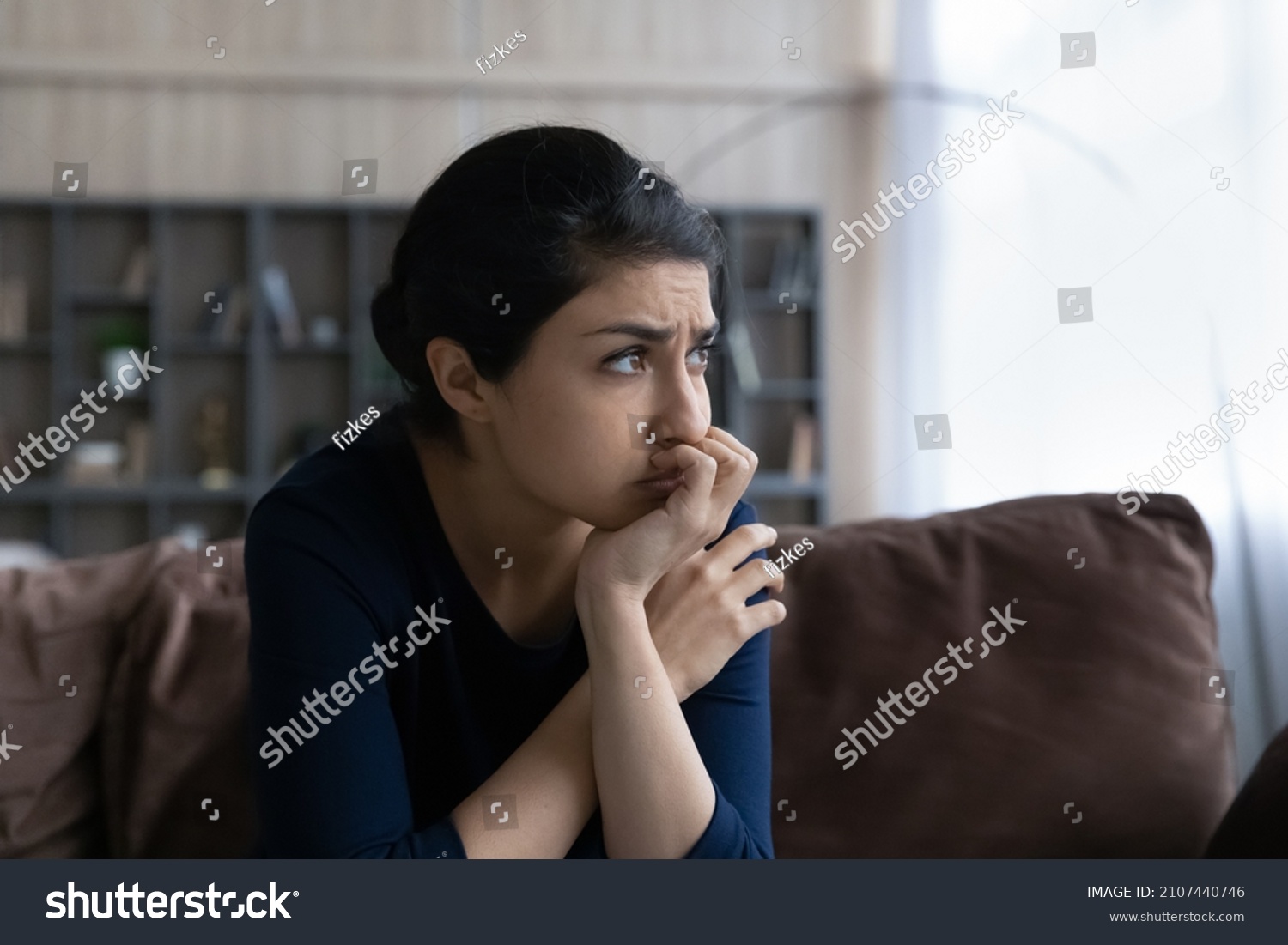 Thoughtful stressed young Indian ethnic woman looking in distance, considering psychological problem solution, suffering from depression or feeling doubtful making difficult decision at home. #2107440746