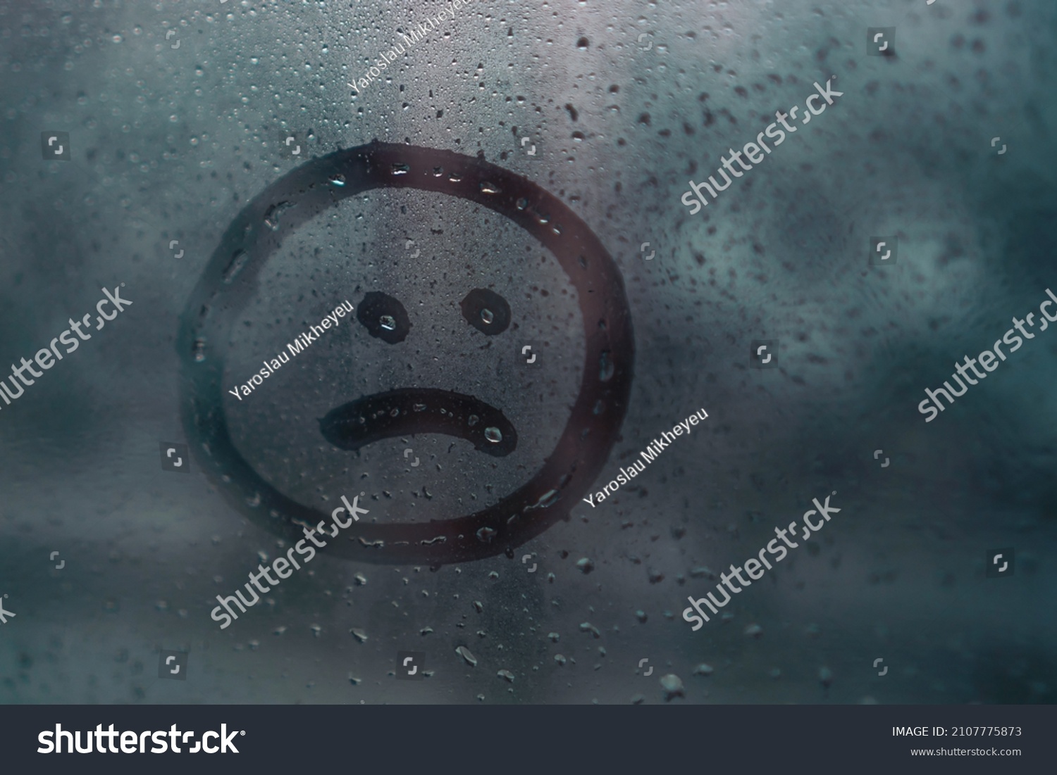 Sad smiley drawn by hand on wet fogged glass from the rain, copy the space. Concept of loneliness, sadness, bad weather #2107775873