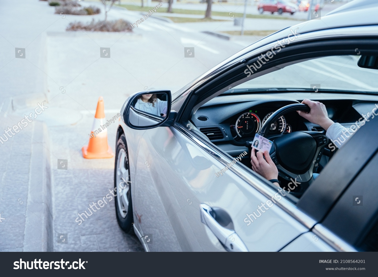 Close up of womand hands on wheel with driving license. Driving school concept. #2108564201