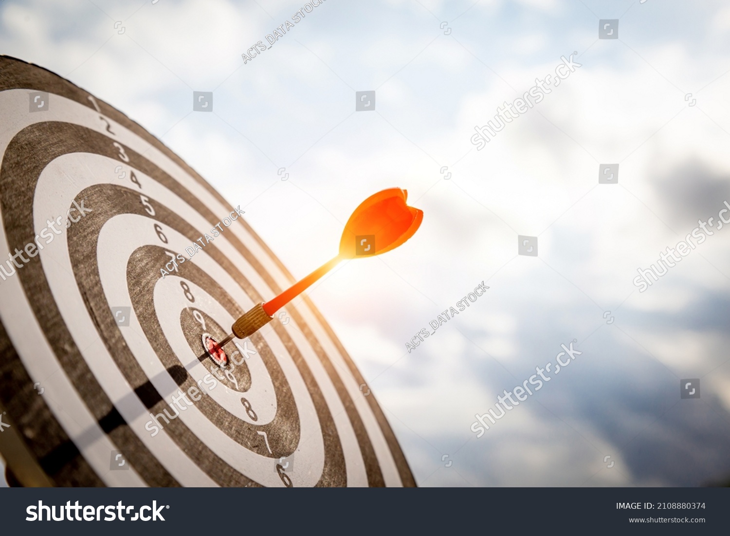 Close up shot red darts arrows in the target  of dartboard center on dark blue sky background. Business target or goal success and winner concept. #2108880374