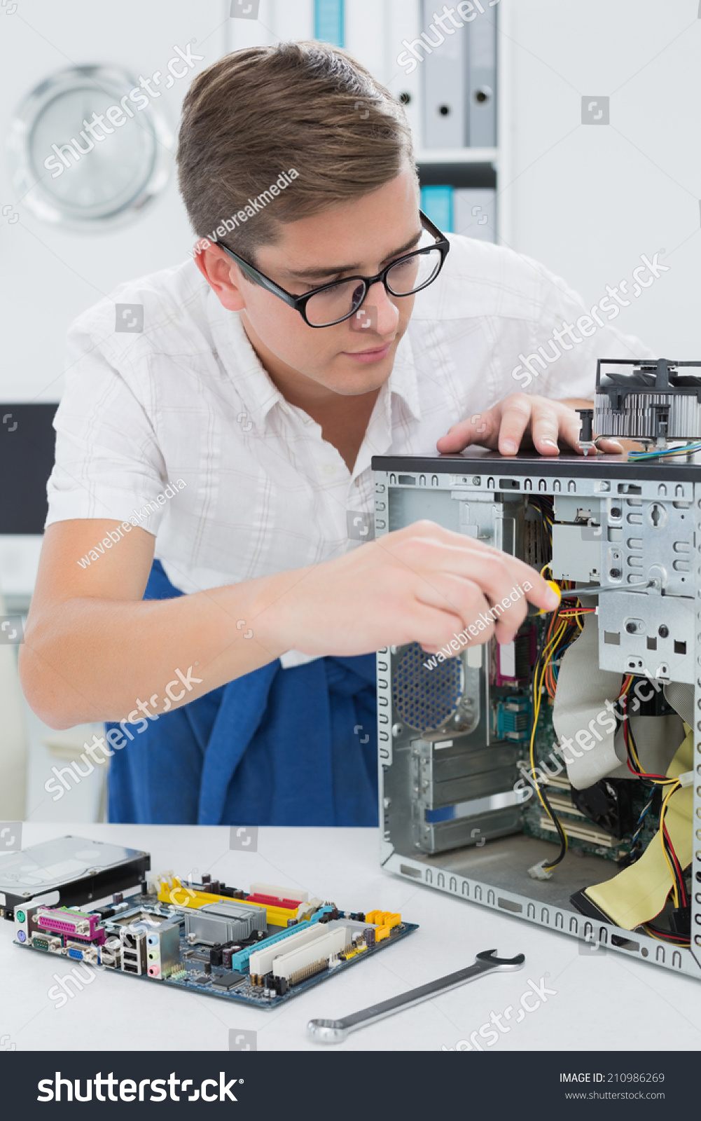 Young technician working on broken computer in his office #210986269