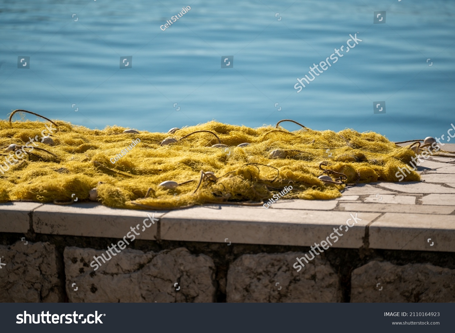 fishing nets dry on shore. Fishing net near dock. Stacked yellow coloured fishing nets. fishing nets dry on shore near dock. Yellow coloured fishingnets #2110164923