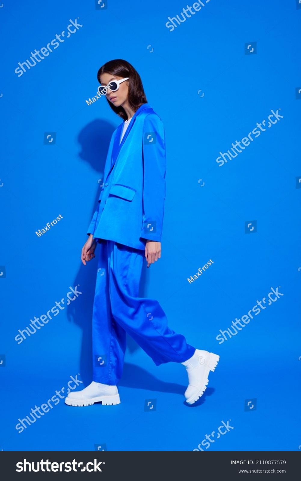 Fashion asian female model in blue suit, white boots and sunglasses. Asian fashion #2110877579