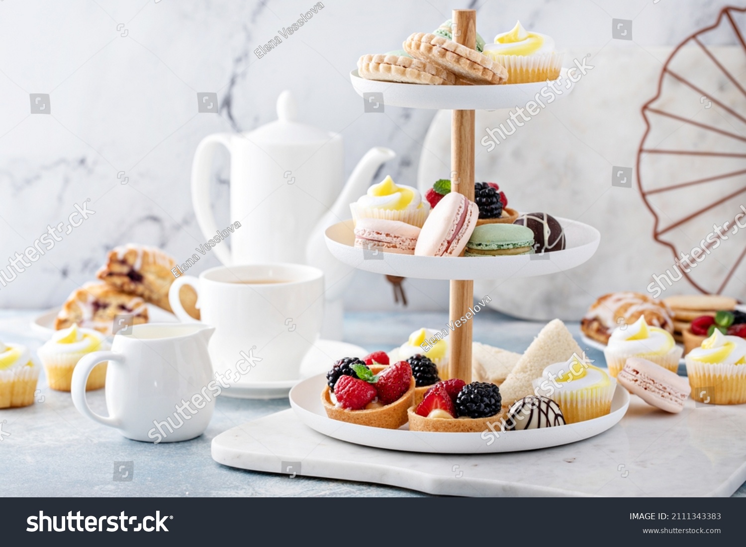 Spring or summer dessert table, three tiered tray with variety of desserts and sandwiches for tea #2111343383