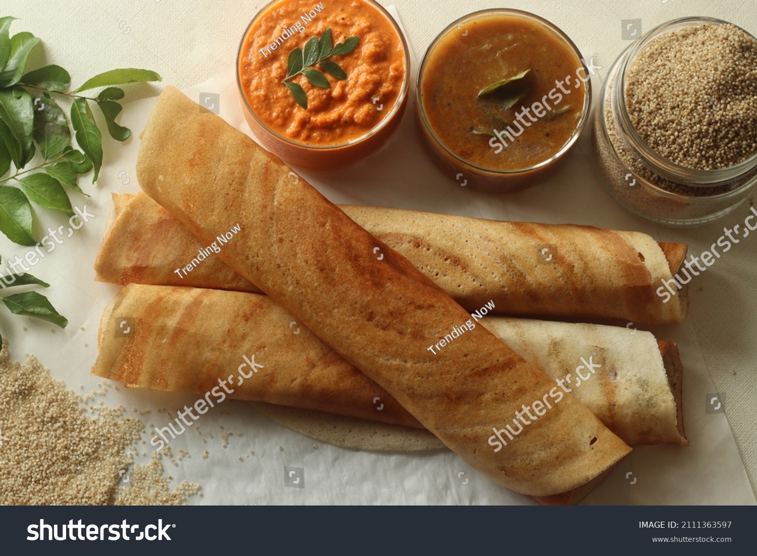 Crispy crepes made of little millets and lentils. Commonly known as little millet dosa. Plated as dosa rolls. Served with coconut spicy condiments and sambar. Shot on white background #2111363597