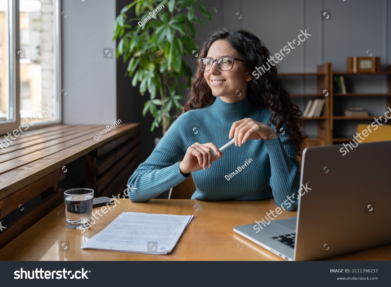 Positive happy female employee resting at workplace, looking away from computer screen. Relaxed woman office worker taking break to refresh mind and prevent stress during workday. Employee wellbeing #2111396237