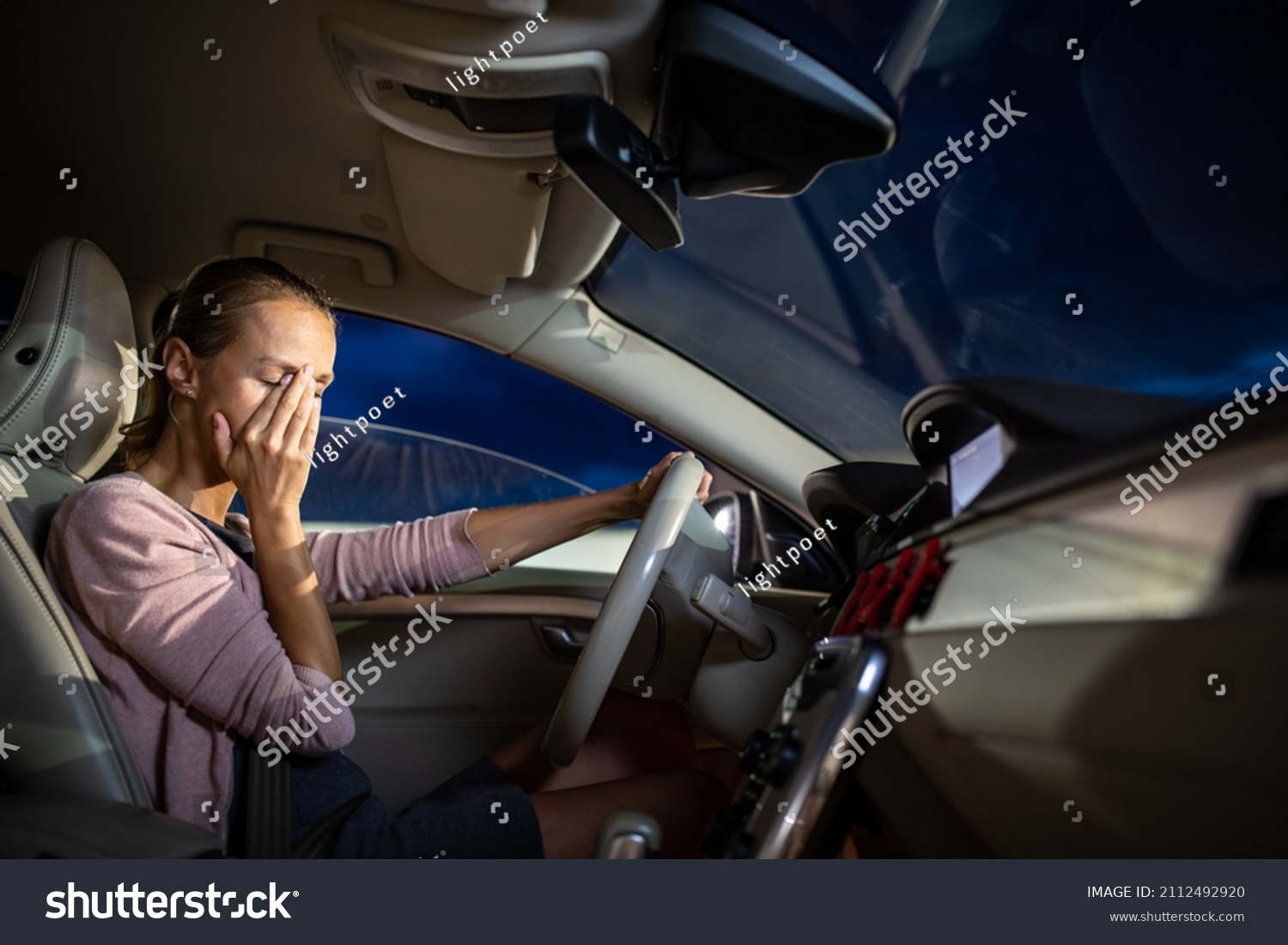 Young female driver at the wheel of her car, super tired, falling asleep while driving in a potentially dangerous situation - Road safety concept #2112492920