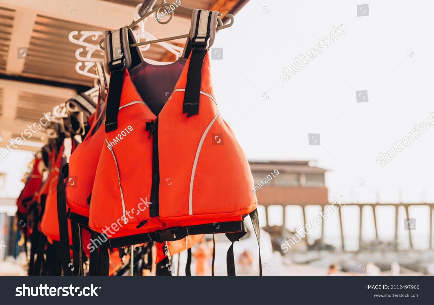 Life jacket on rail for costumer, Red Life jacket with black belts, Personal flotation device. Life jacket ready to be used by tourist going on a boat trip. #2112497900