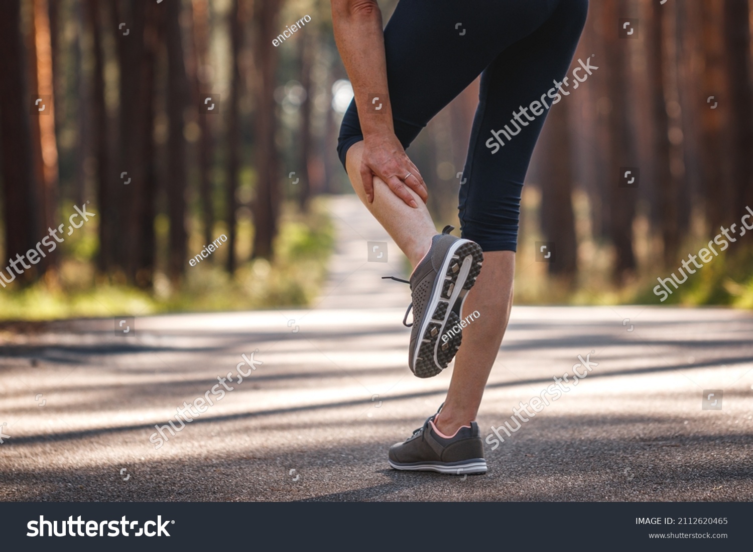 Woman feeling pain of her leg during jogging. Calf muscle cramp. Underestimating the warm-up exercise before running #2112620465