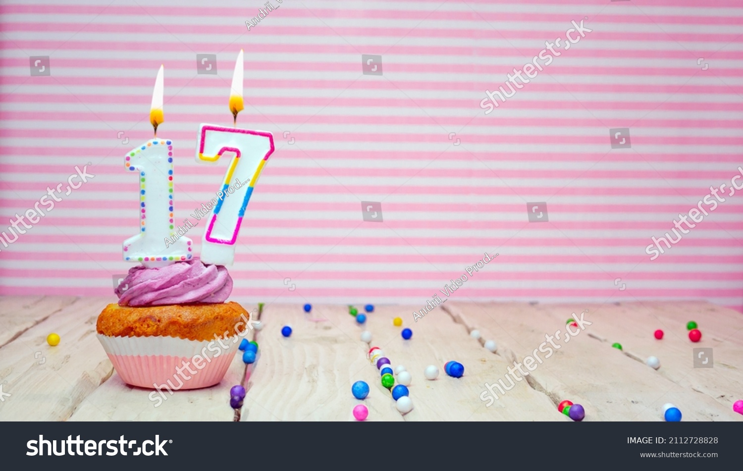 Muffin with cream and number 17 for a birthday on a pink background, copy space, holiday background. Happy birthday greetings for seventeen years old #2112728828