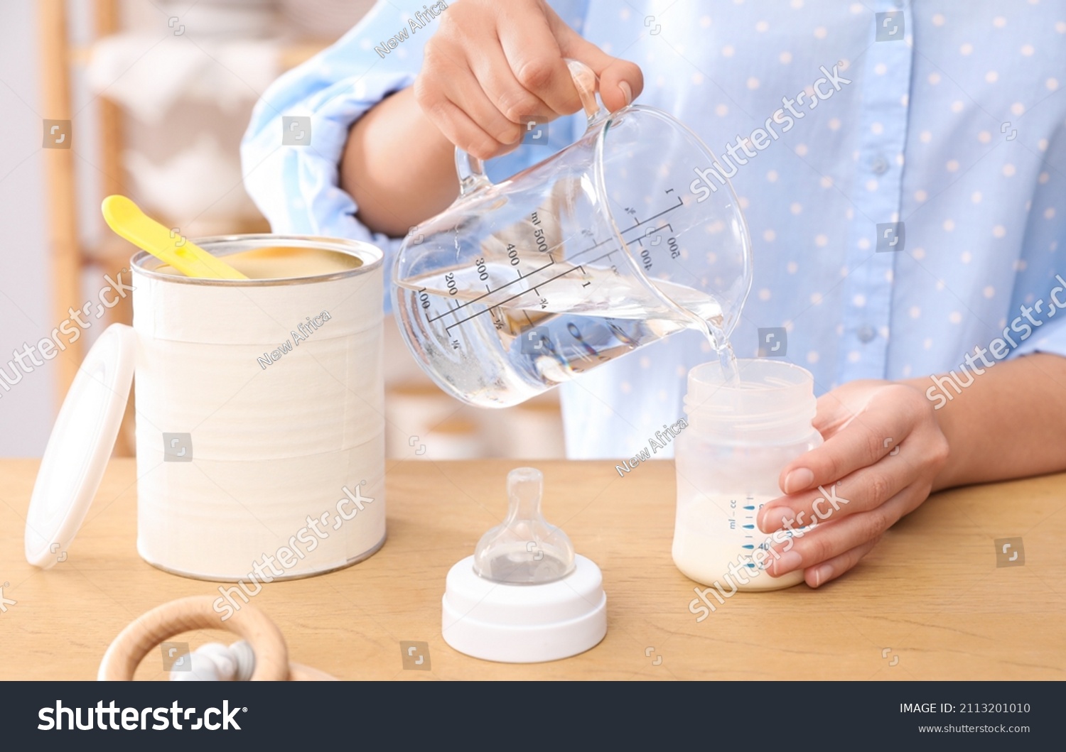 Woman preparing infant formula at table indoors, closeup. Baby milk #2113201010